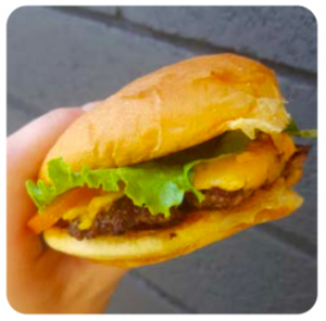 A cheeseburger is held in a close-up shot.