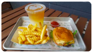A hamburger, fries, and drink meal on a silver tray, framed in the center and on a slatted table.