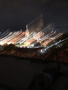 A city skyline at night with buildings lit up. The image has been overexposed so the lights are stretched out.