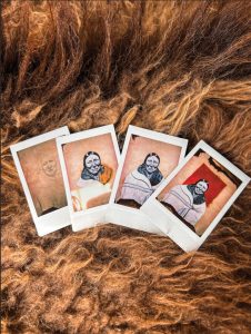 Four polaroids of different stages of the previously showing artwork as a sketch, partially colored, and fully colored in.