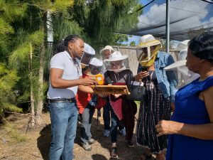 Alwyn Simeina with bee frame in hand educating community group outside