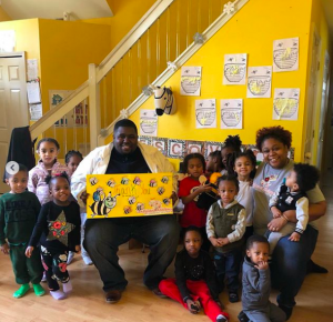 Timothy Jackson holds paper of bee art with young group of kids