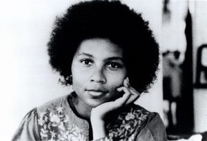 bell hooks as a younger person, pictured resting her head in her hand with a slight smile on her face.