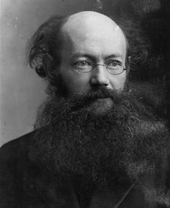 Black and white photographic portrait of Peter Kropotkin circa 1900. Kropotkin is of older age with a large beard and mustache and glasses. He looks over the right shoulder of the viewer.